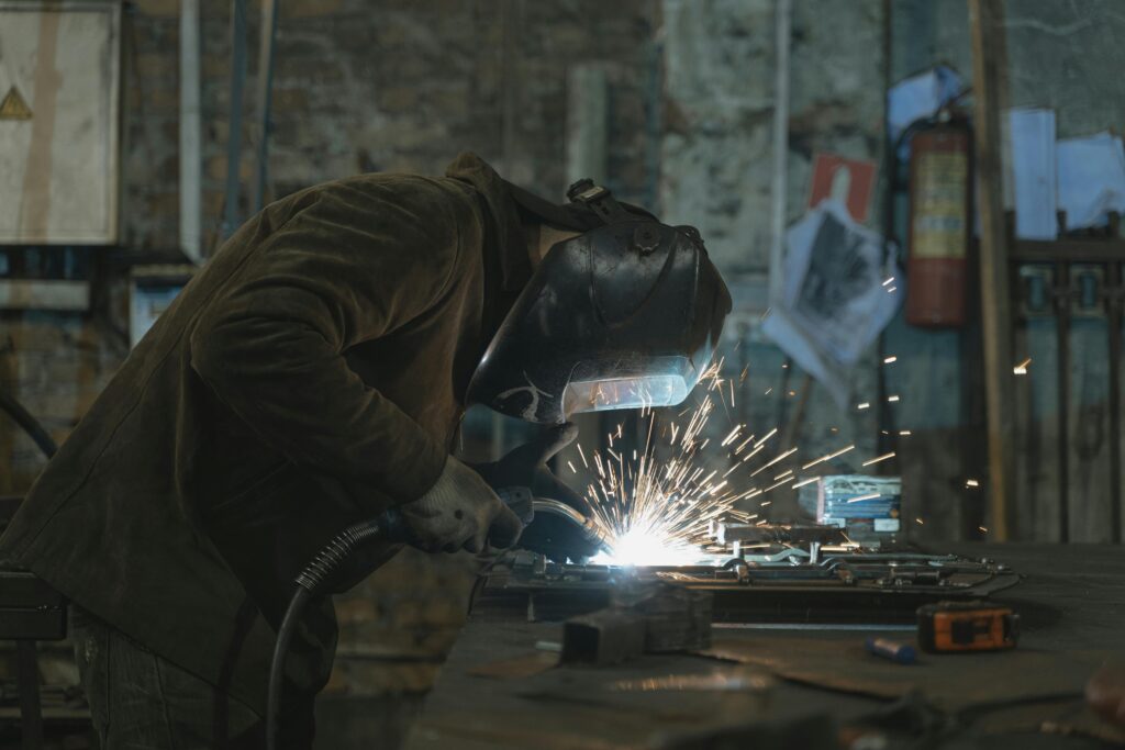 pexels-photo-5846247-5846247 A skilled welder focused on welding a metal piece in an industrial workshop. Sparks flying vividly.